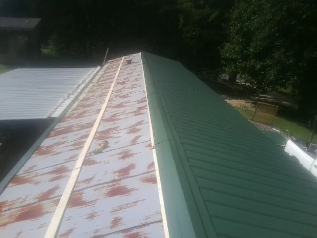 Old rusted panels beside newly installed green metal roofing — Wind Damage Roof Repair by Roofing Brothers in Linden